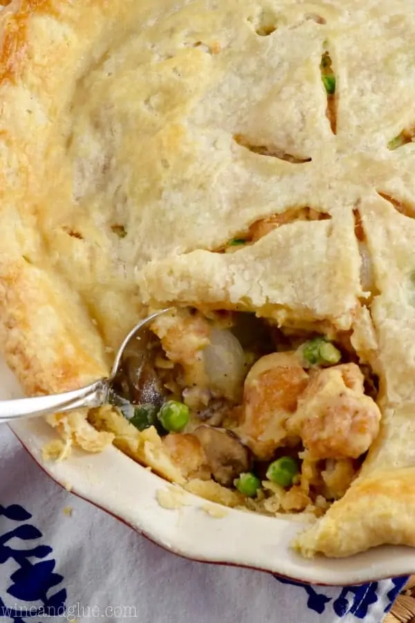 A large slice has been cut out of the Shrimp Pot Pie showing the creamy middle with peas, mushrooms, pearl onions, and shrimp. 