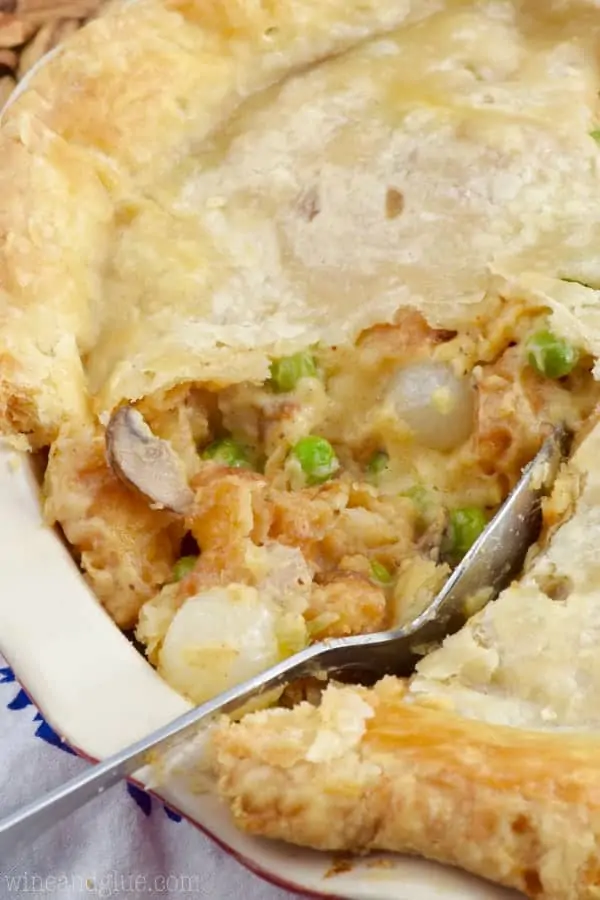 A large slice has been cut out of the Shrimp Pot Pie showing the creamy middle with peas, mushrooms, pearl onions, and shrimp. 