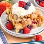 Pinterest graphic for Berry French Toast Casserole recipe. Image is photo of a piece of Berry French Toast Casserole served on a plate garnished with berries and whipped cream. Cup of coffee and bowl of berries in background. Text says, "Berry French Toast Casserole simplejoy.com"