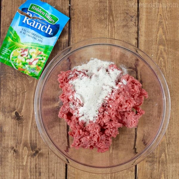 Hidden Valley Ranch Packet has been poured on top of ground beef in a glass bowl. 