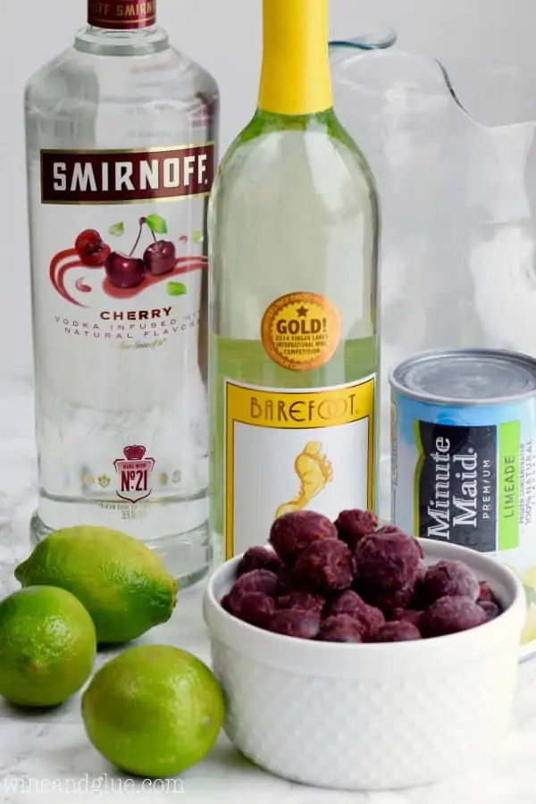 A picture of the ingredients of the Cherry Limeade Sangria (Limes, Minute Maid's Limeade, White Wine, Smirnoff's Cherry vodka, and frozen cherries). 