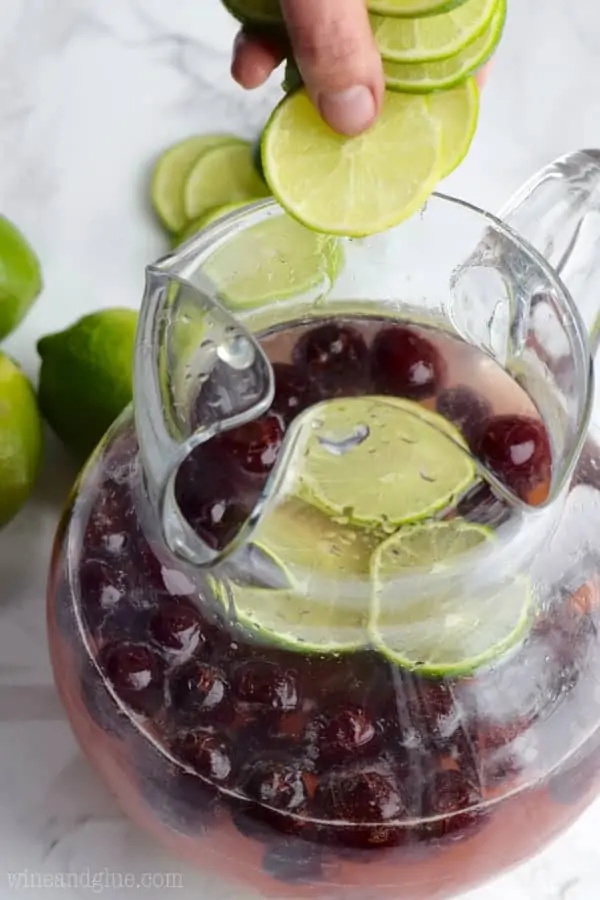 Slices of lime are being placed into the pitcher. 