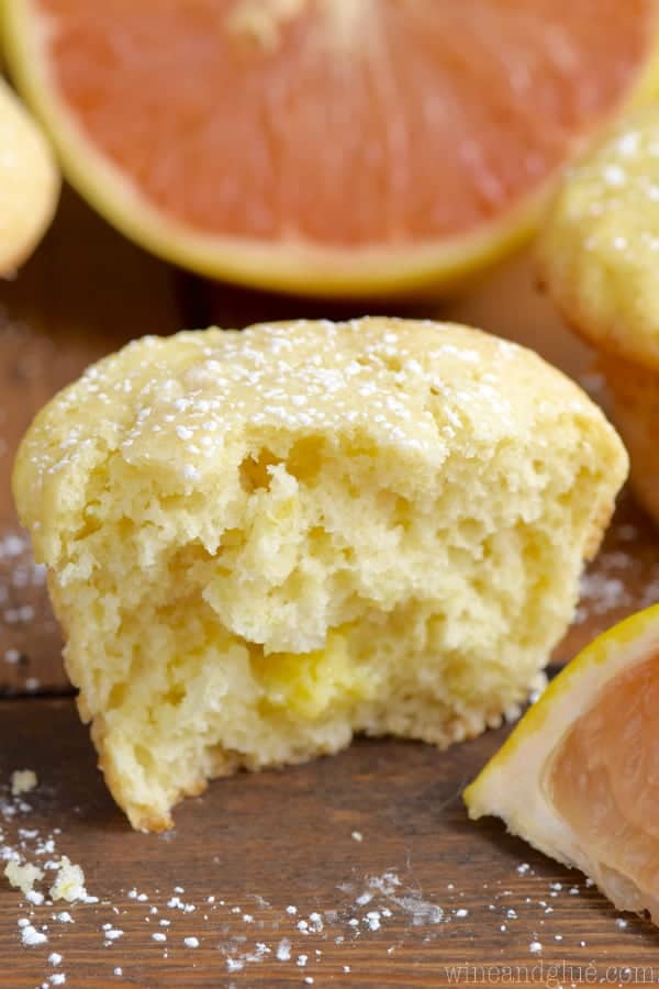 A large bite is taken out of the Grapefruit Muffin showing the airy interior and sprinkled with powdered sugar. 