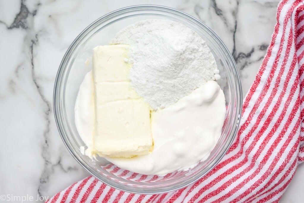 overhead of a bowl whipped cream with a block of cream cheese and dry pudding mix