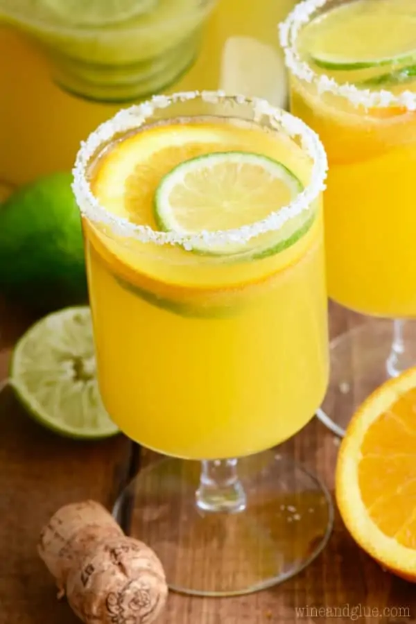 In a glass, the Mimosa Margaritas is rimmed with flaky salt and slices of lime and oranges float in the liquid. 