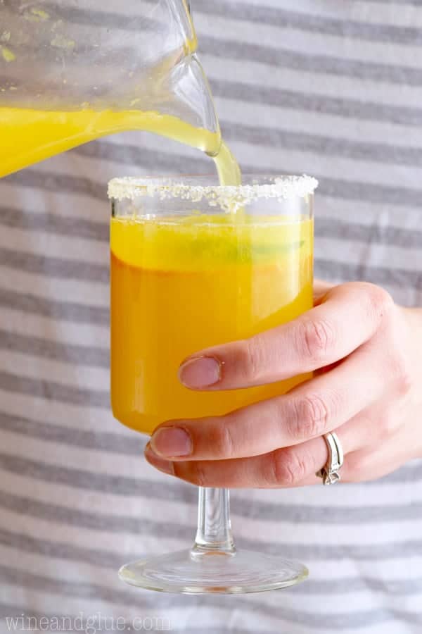A woman pouring the Mimosa Margarita into a glass rimmed with salt. 