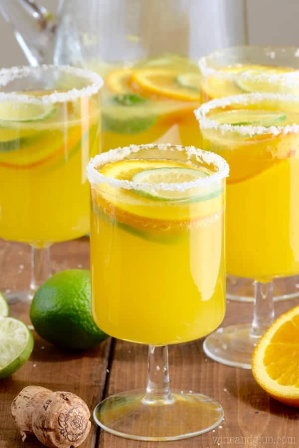 In a glass, the Mimosa Margaritas is rimmed with flaky salt and slices of lime and oranges float in the liquid. 