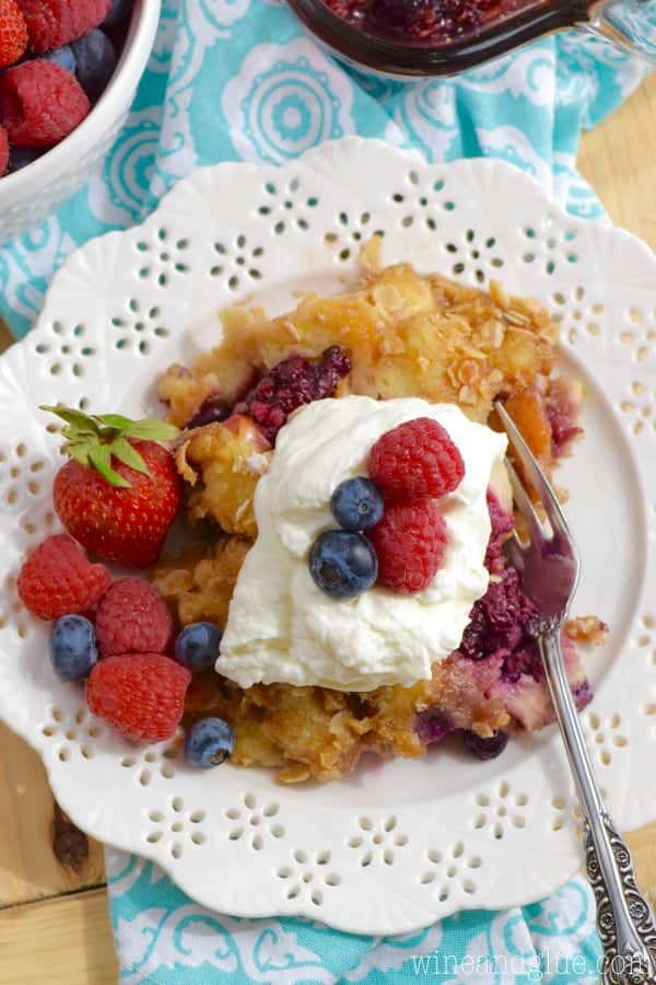 An overhead photo of the Overnight Berry Cobbler French Toast on a white plate and topped with homemade whipped cream and berries. 