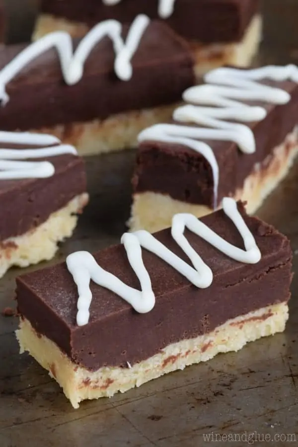 The Sugar Cookie Fudge Bars are in rectangular shapes showing the specific layers of the cookie and fudge and topped with a white frosting zig zag. 