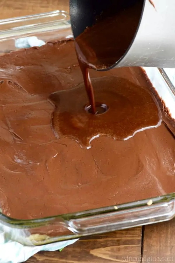 Chocolate is being poured onto the fudge layer in the Sugar Cookie Fudge Bars. 