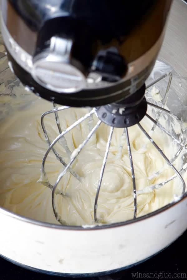 overhead view of black kitchen aid mixer with the whisk attachment making cream cheese frosting