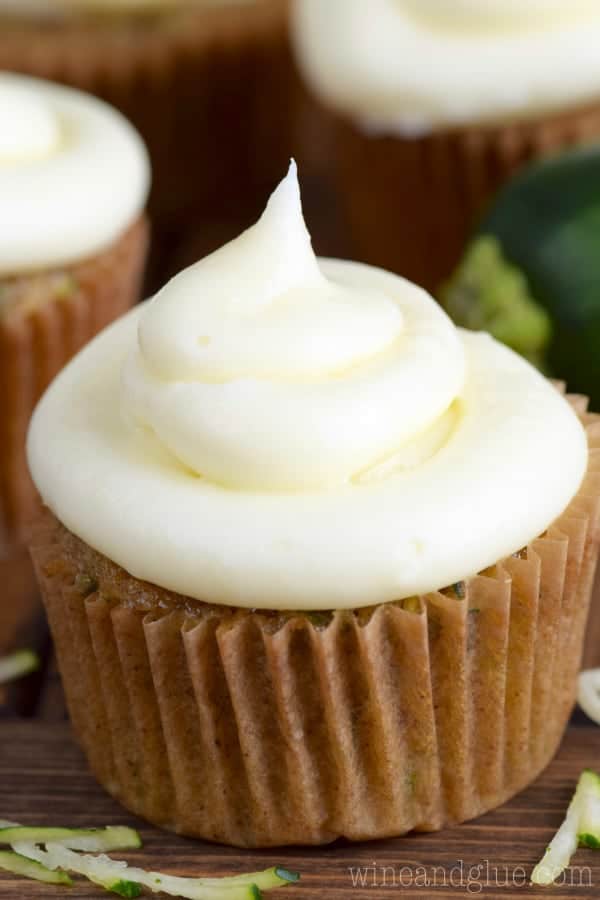 In a cupcake tin, the Zucchini Cupcake has a dark golden brown color topped with a fluffy cream cheese frosting. 