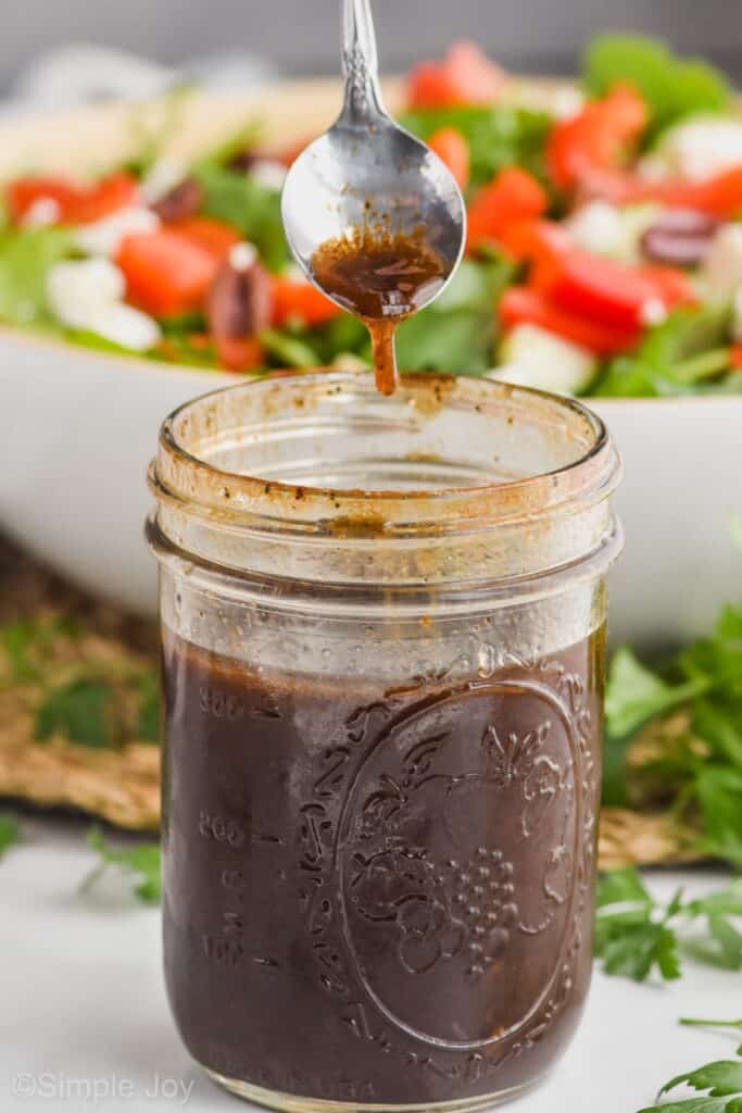 a mason jar with balsamic dressing recipe and a spoon dripping some into it