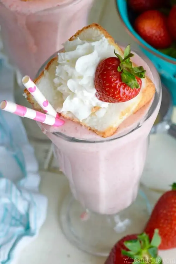 An overhead photo of the Boozy Strawberry Shortcake Milkshake with a small slice of the strawberry shortcake, a strawberry, and whipped cream. 