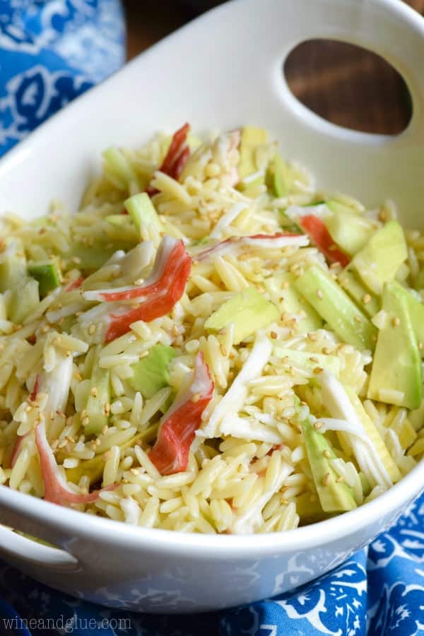 White bowl filled with orzo pasta salad recipe topped with white sesame seeds. 