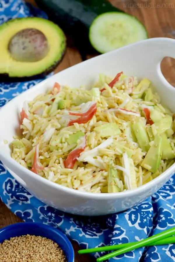 White bowl filled with orzo pasta salad recipe topped with white sesame seeds. 