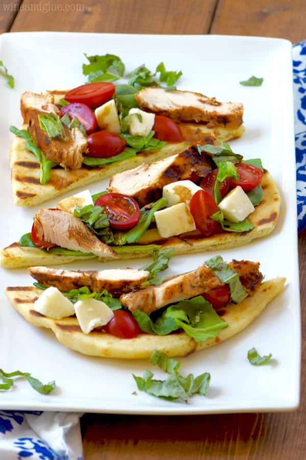 On a white plate, three Grilled Chicken Capese Flatbread. 