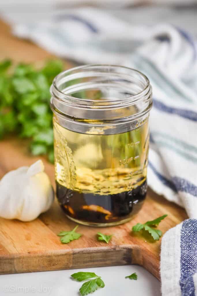 a mason jar with the ingredients for balsamic dressing, you can see the oil separated from the vinegar and the other ingredients floating in the middle