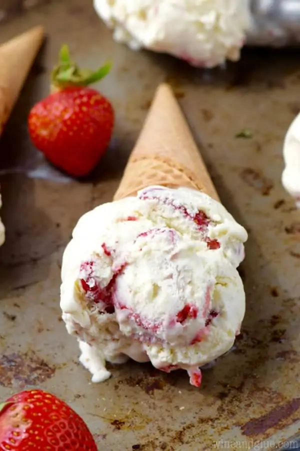 On a baking sheet, a scoop of the Strawberries and Cream Ice Cream in a waffle cone. 