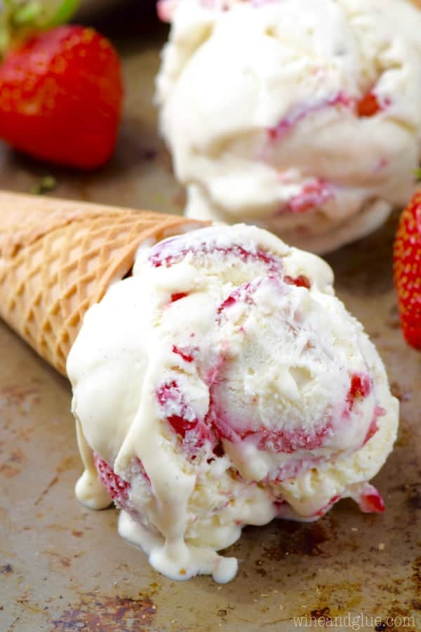 On a baking sheet, a scoop of the Strawberry and Cream Ice Cream in a waffle cone. 