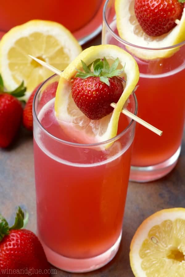 The Strawberry Lemonade Beergaritas is in in a tall glass and topped with a sliced lemon covering a strawberry in a toothpick. 
