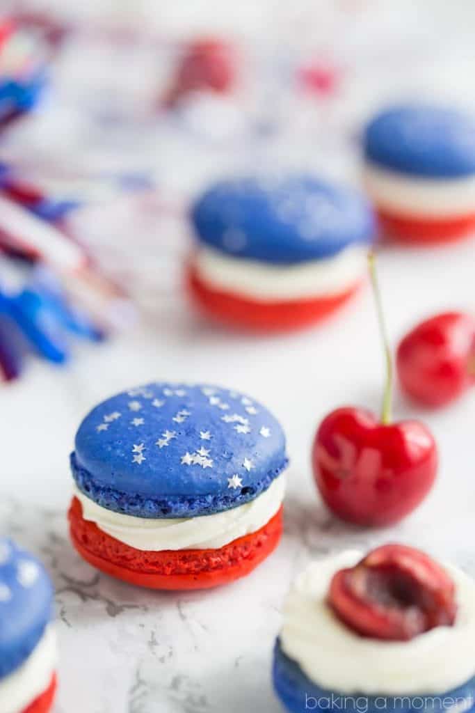 The Red, White, and Blue Cherry Cheesecake Macarons has a white frosting, and one cookie is red and the other blue with star sprinkles. 