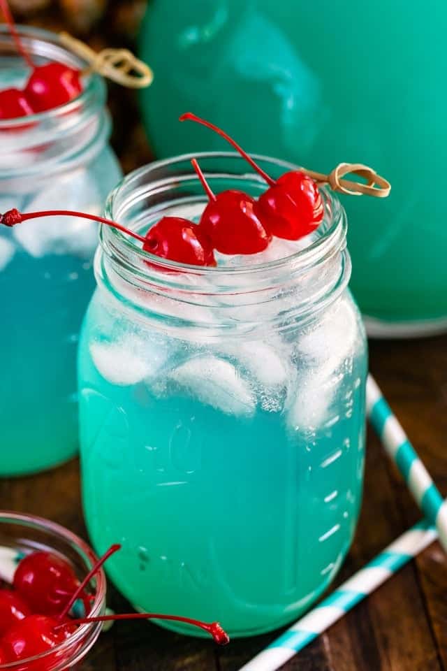 The Blue Hawaiian Party Punch has a turquoise blue color topped with three cherries. 