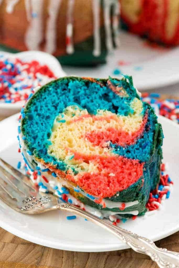 The Fireworks Bundt Cake has white, red, and blue colors swirled into it and white frosting was dripped on top. 