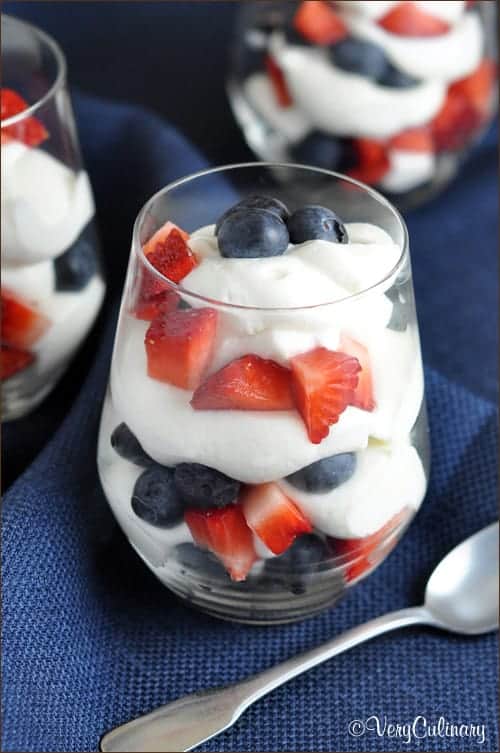In a clear glass, the Red White and Blue Cheesecake Mousse has diced strawberries and blueberries and with white cheesecake mousse. 