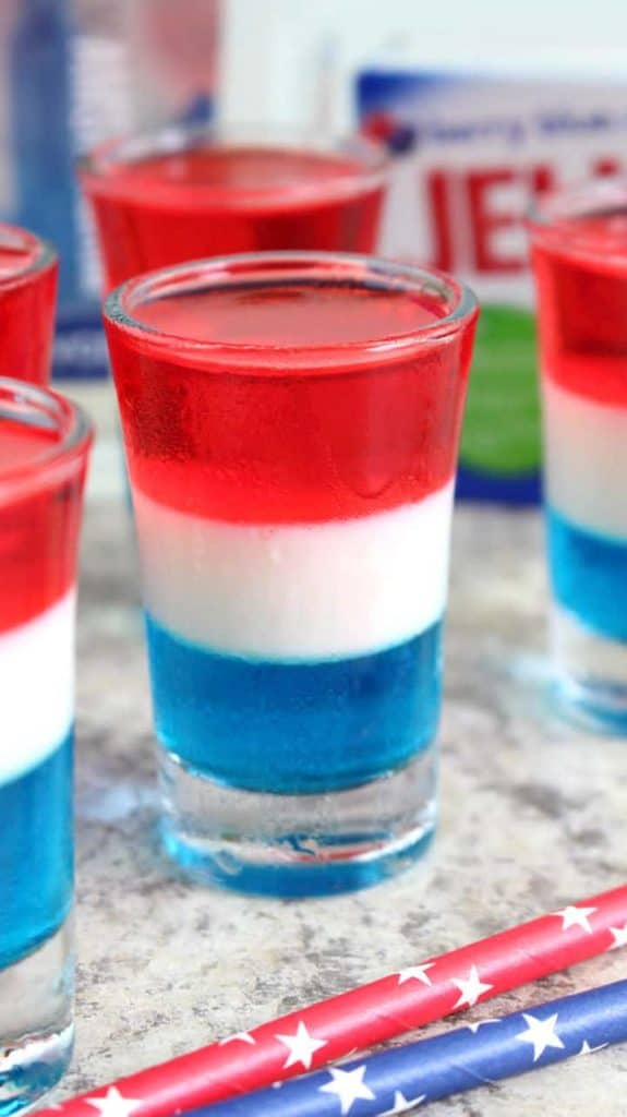 In a jello glass, the Layered Jello Shots has distinct layers of blue, white, and red. 