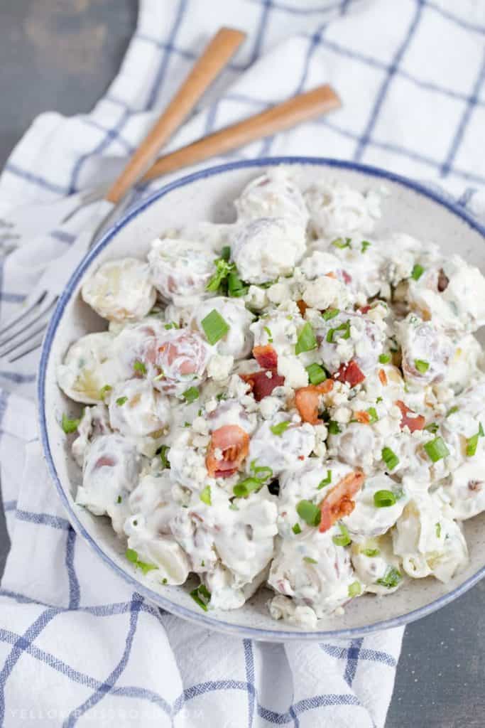 The Red, White, and Blue Cheese Potato Salad is topped with sliced bacon and chives. 