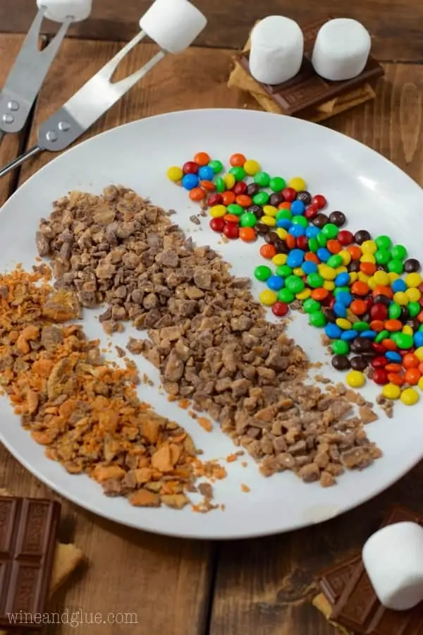 On a white plate, there are distinct rows of the Candy Coated S'more's coating (broken pieces of Butterfingers, M&Ms, and toffee)