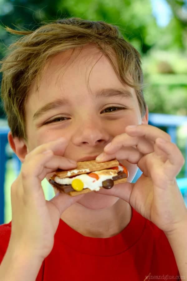 A little boy eating the Candy Coated S'mores that has M&Ms as the coating. 