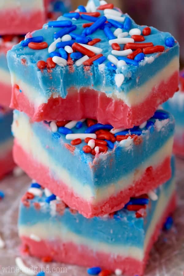 Three Red, White, and Blue Fudge are stacked up on top of each other showing the distinct colored layers and topped with red, white, and blue sprinkles.