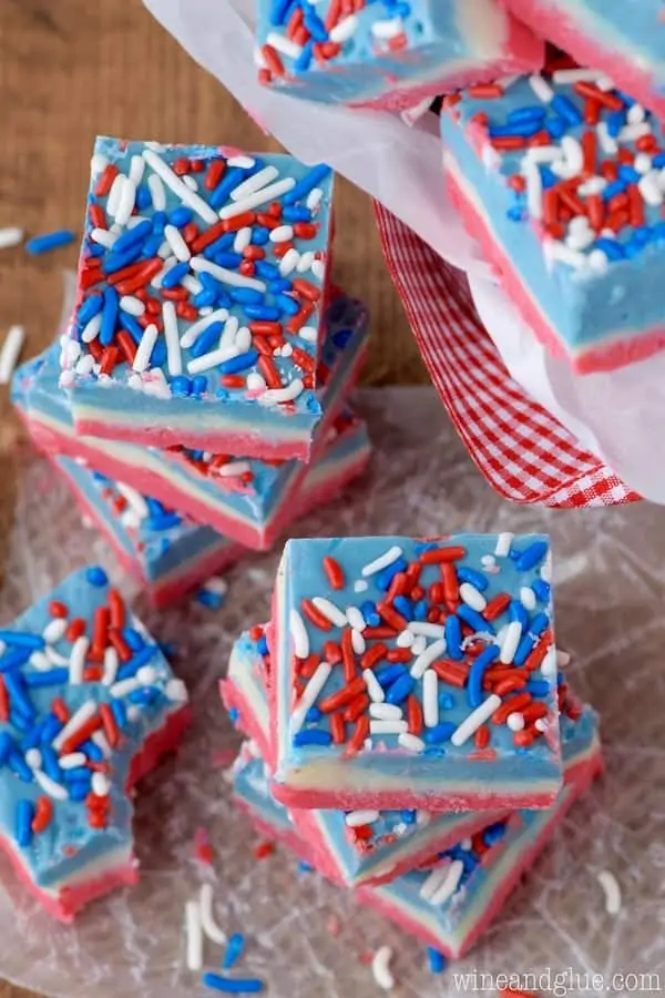 The Red, White, and Blue Fudge are stacked on top of each other and has the distinct colored layers and topped with red, white, and blue sprinkles. 