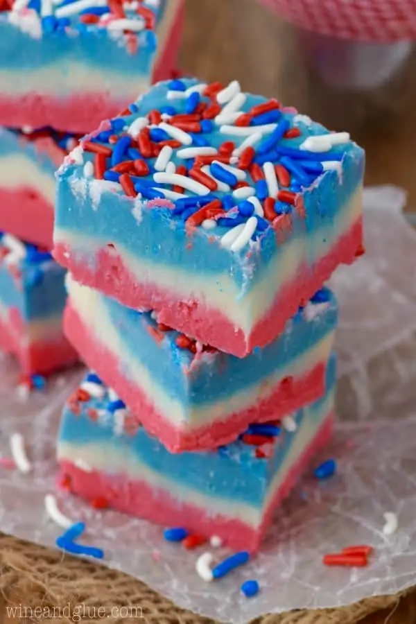 The Red, White, and Blue Fudge are stacked on top of each other and has the distinct colored layers and topped with red, white, and blue sprinkles. 