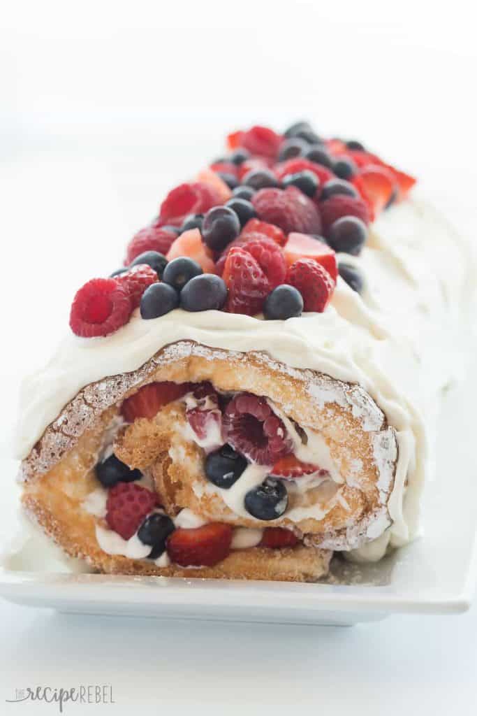 The Triple Berry Angel Food Cake Roll has a fluffy angel cake. In the filling and on top, there are blueberries, raspberries, and cut up strawberries. 