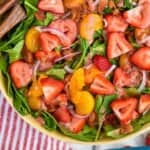 pinterest graphic of overhead of a strawberry salad with sliced strawberries, mandarin oranges, bacon, and red onions