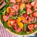 pinterest graphic of overhead of a strawberry salad with sliced strawberries, mandarin oranges, bacon, and red onions