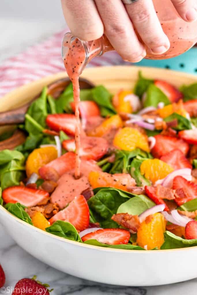 strawberry salad dressing being poured onto a salad