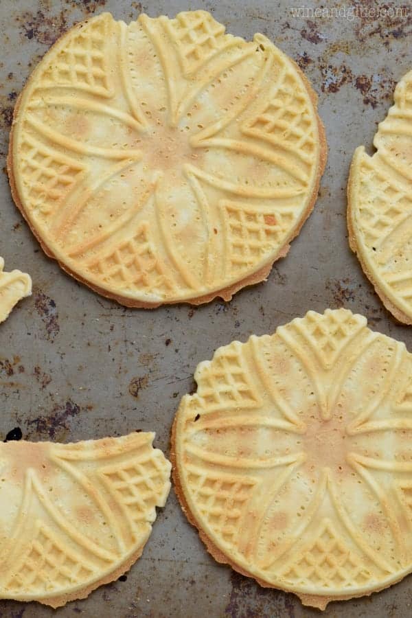On a baking tray, the Belgian Waffles Crisps have a golden color and beautiful waffle designs of a 5 petaled flower. 