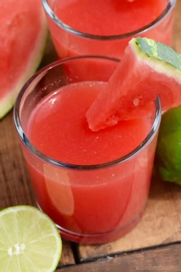 In a glass, the Watermelon Limeade has a red color and a slice of watermelon on the rim. 