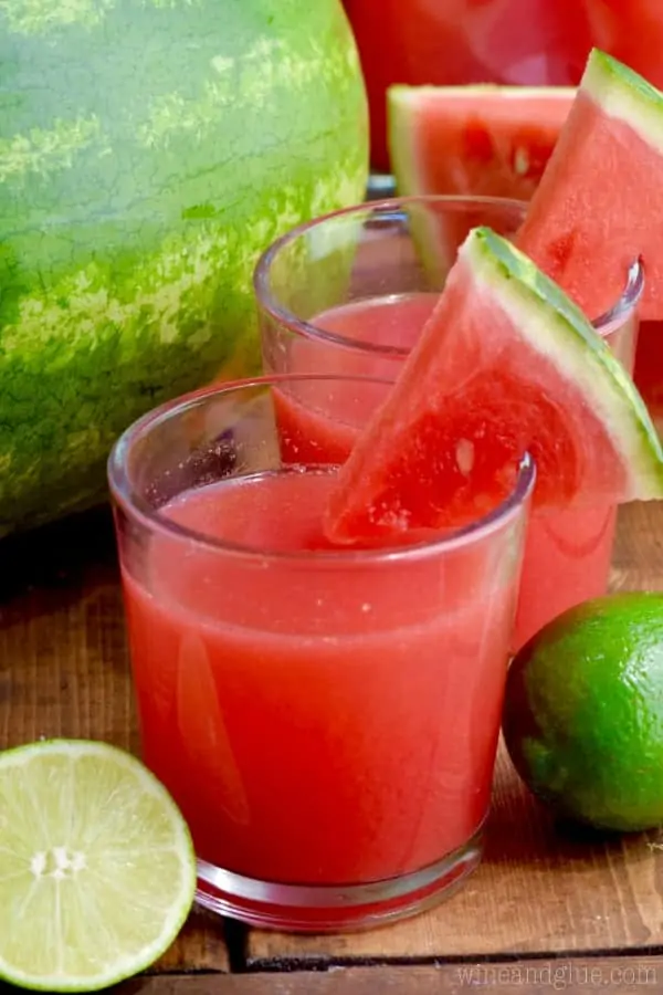 In a glass, the Watermelon Limeade has a red color and a slice of watermelon on the rim. 