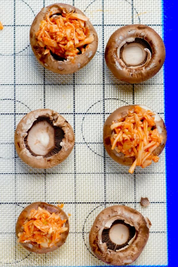 On a overhead photo of the Buffalo Chicken Stuffed Mushrooms showing that some of the mushrooms' stems are taken out. 