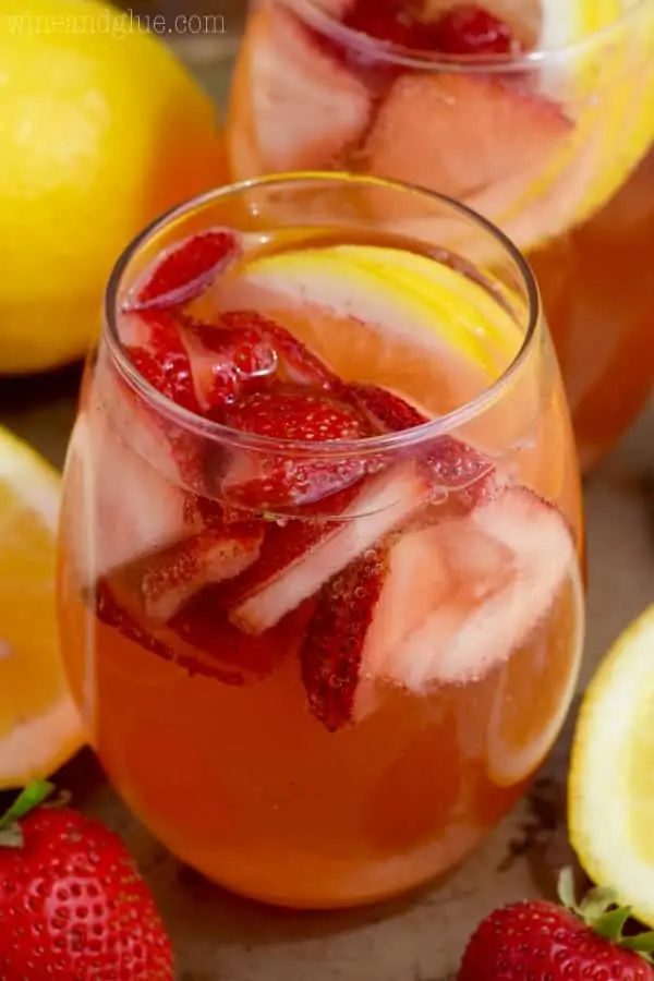 In a glass, the Strawberry Lemonade Spritzers have a light pink color with sliced strawberries and lemons. 