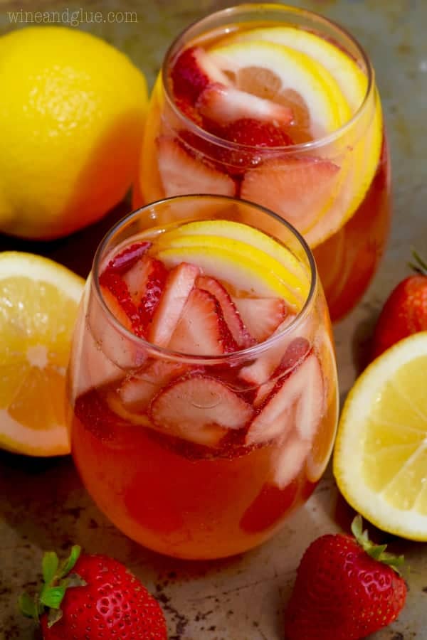 In a glass, the Strawberry Lemonade Spritzers have a light pink color with sliced strawberries and lemons. 