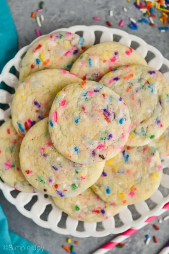 overhead view of a white plate with funfetti cookies, a teal napkin near them, and sprinkles all around the plate