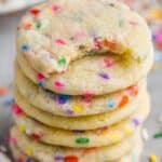 stack of sugar cookies with sprinkles with the top one missing a bite, sprinkles around the stack, and two striped straws - 7