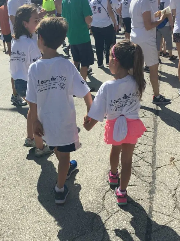 Two children holding hands wearing Team Elliot t-shirts.  