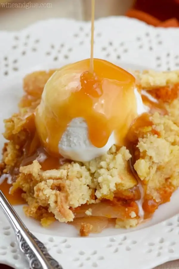 The Apple Pumpkin Dump Cake as a single scoop of vanilla ice cream on top while caramel is being poured. 